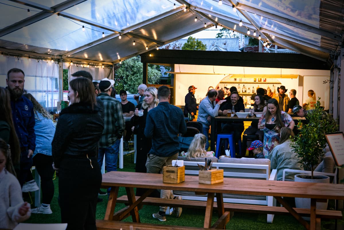 Many customers enjoying the Queen of the West Beer Garden at dusk, lit up by the subtle lighting.