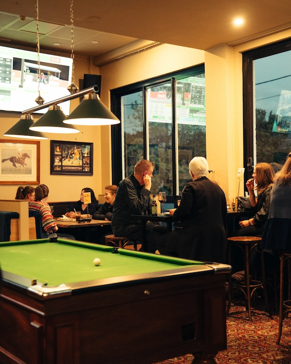 An overview of the Queen of the West Sports Bar showing booths, a pool table, tall tables and chairs, and sports memorabilia.