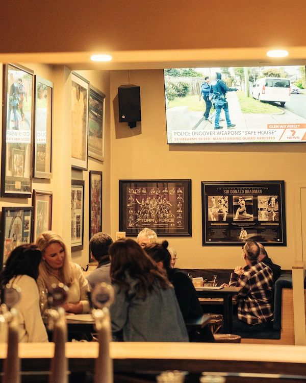 The Queen of the West Sports Bar showing booths, a Wall mounted TV, and customers enjoying each others company.