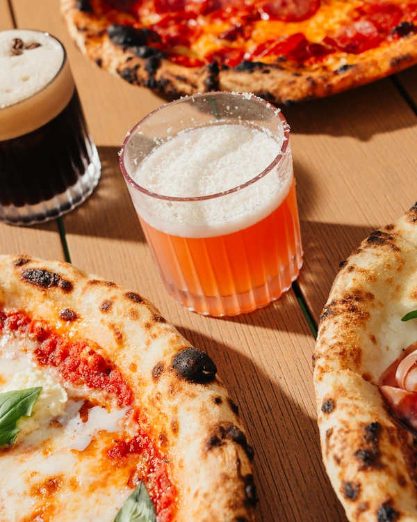 A table filled with cocktails and wood fired pizza