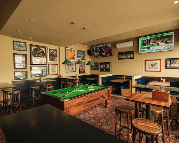 An overview of the Queen of the West Sports Bar showing booths, a pool table, tall tables and chairs and sports memorabilia.